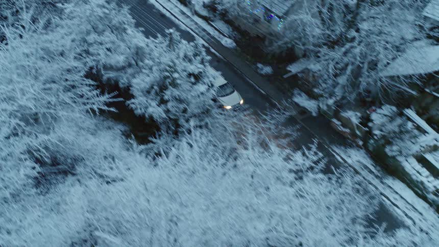 A vehicle driving down the narrow roads of a neighborhood covered in snow