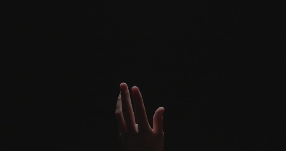 A hand moves through the dark