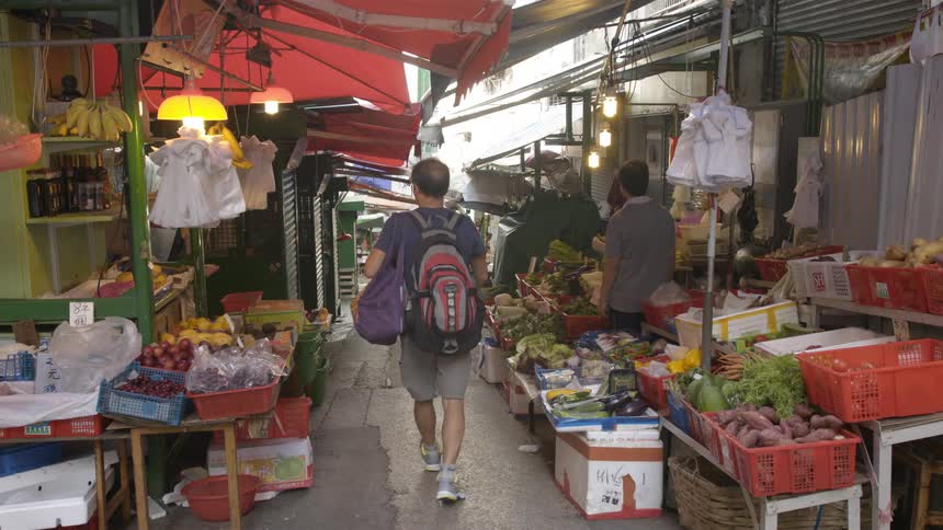 A man walks down the alley of an outdoor food market