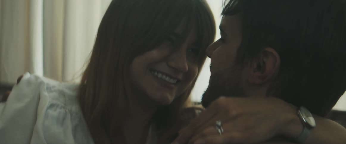 A husband and wife hugging as she shows him a pregnancy test