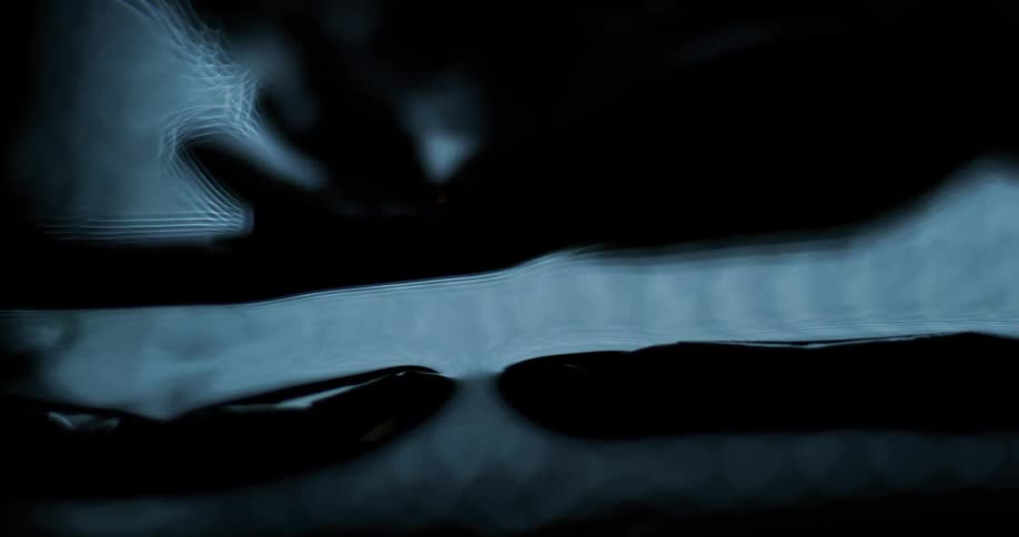 Bright fluid bubbles up and flows around black pieces of rubber