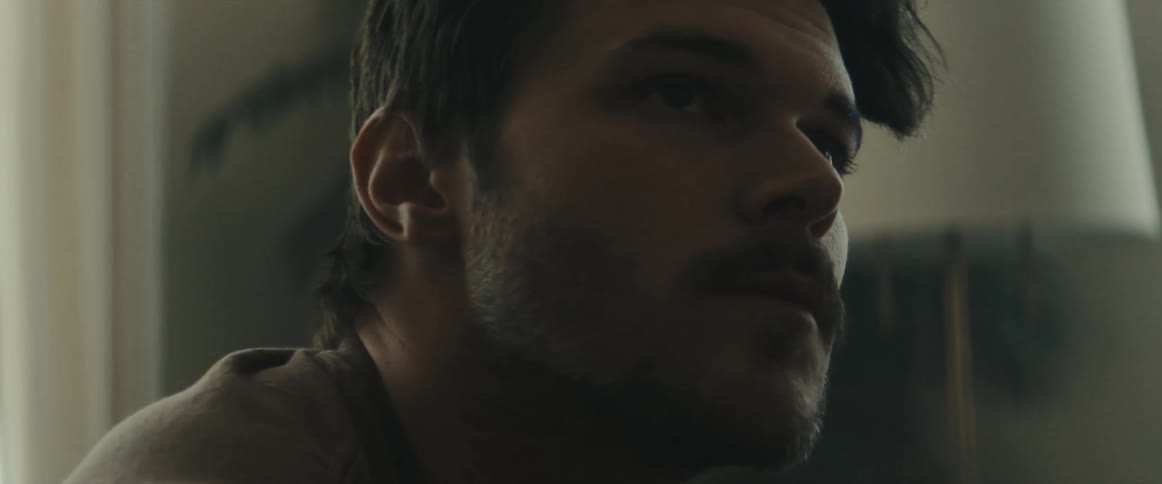 A man sits inside and looks off in to the distance