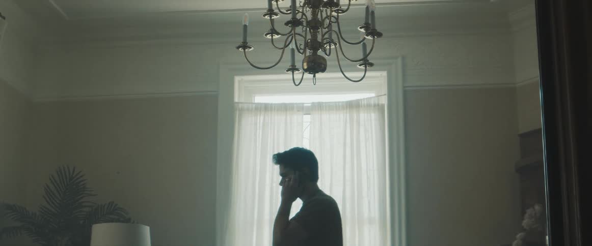 A man walks in a room in his home while talking on the phone
