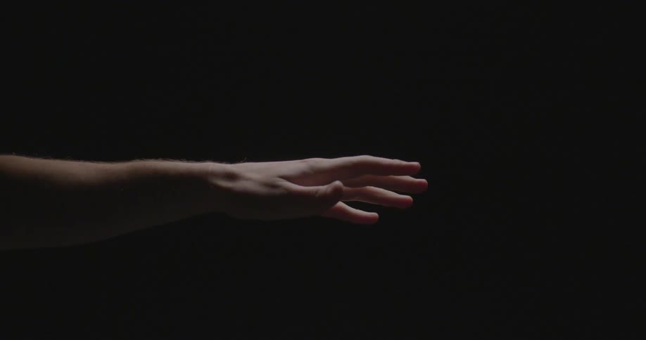 A hand reaching out against a black background