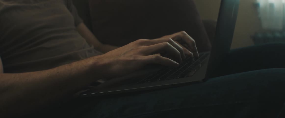 Man sitting on the sofa types on his laptop in the living room