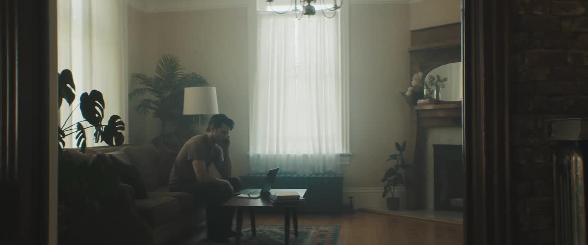A man is sitting in his living room on a couch