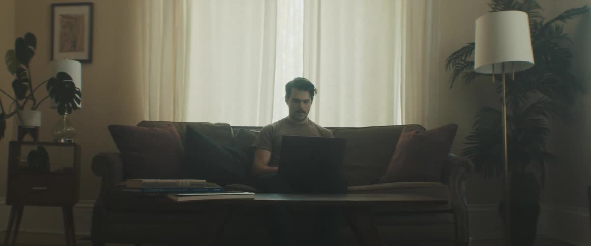 Man sitting on the sofa uses the laptop in the living room