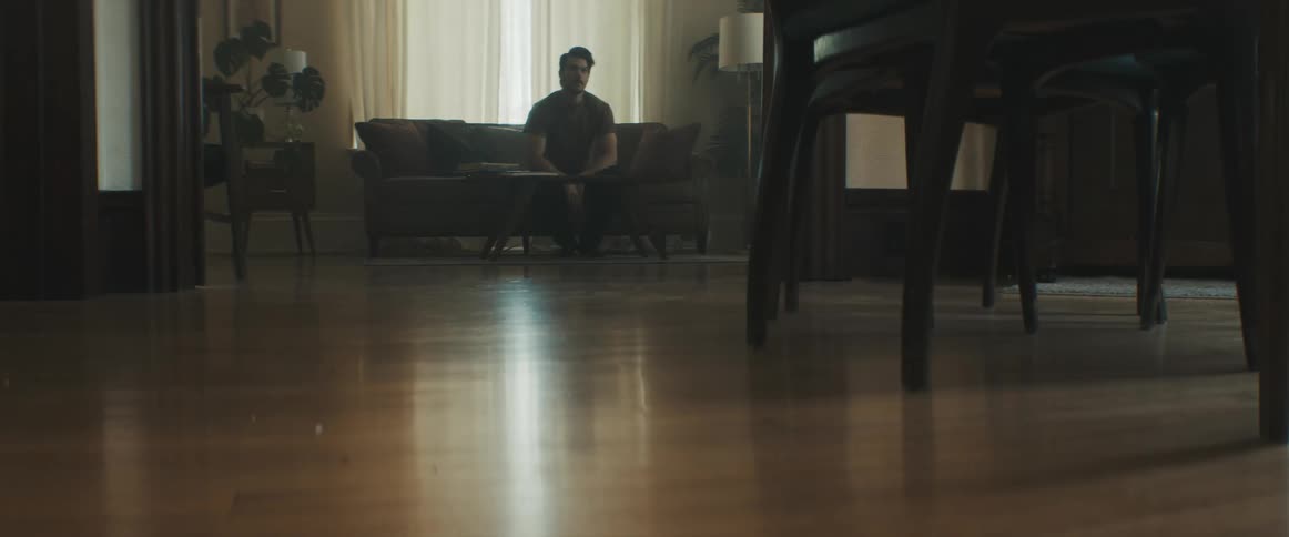 A man sits on the couch and leans back out of frustration or boredom