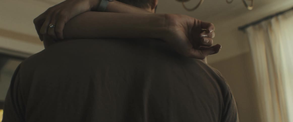 A couple slow dance in their living room and kiss