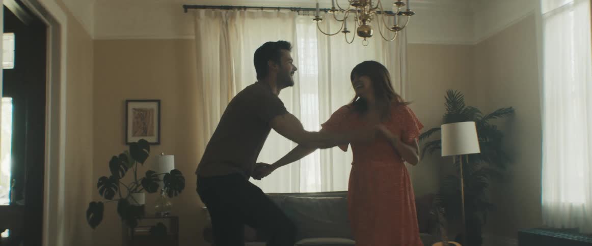 A woman and man are dancing in their house