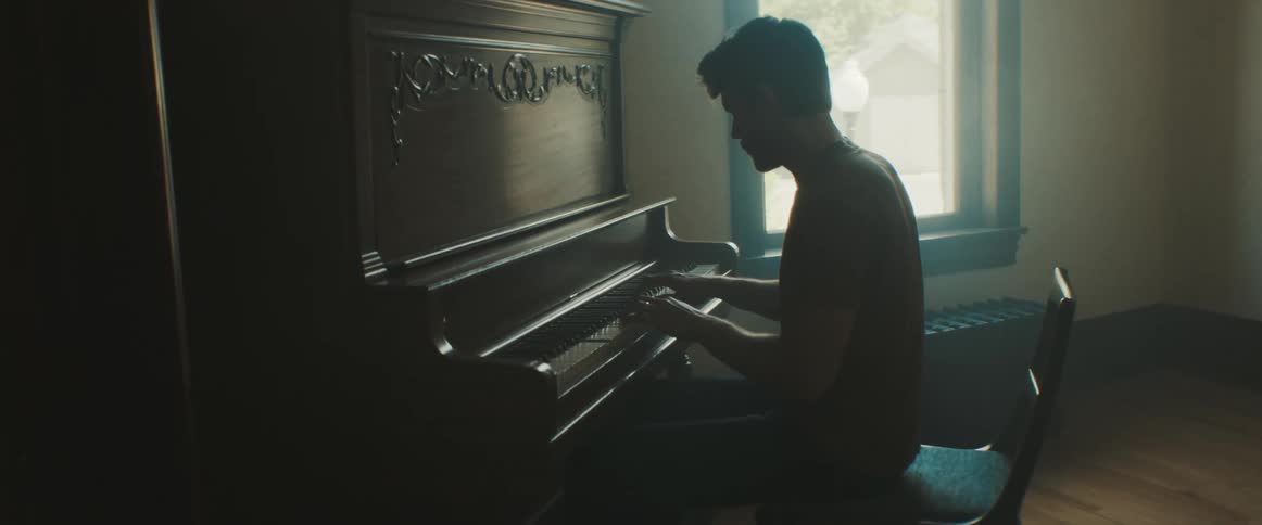 A silhouette of a man plays the piano
