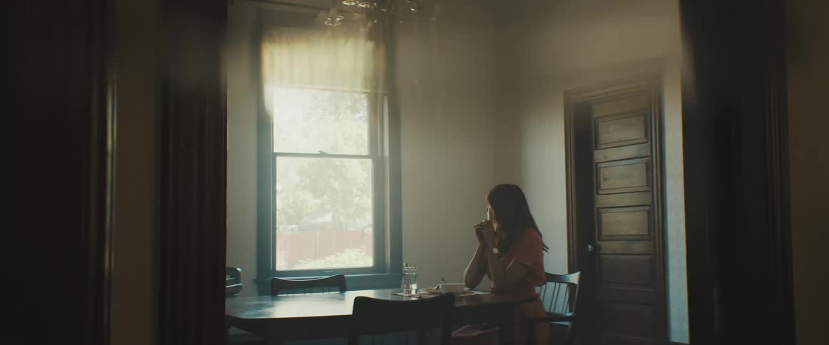 Woman sitting at the table looks out the window in the living room