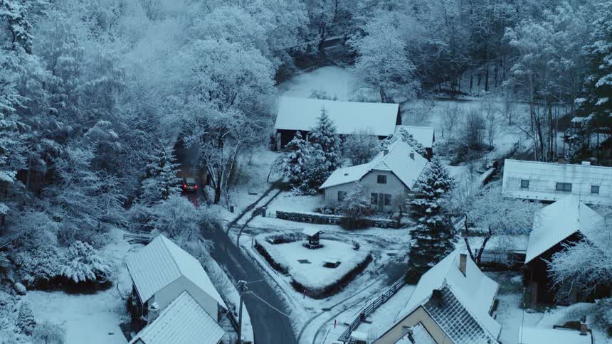 A car drives through a snow covered neighborhood