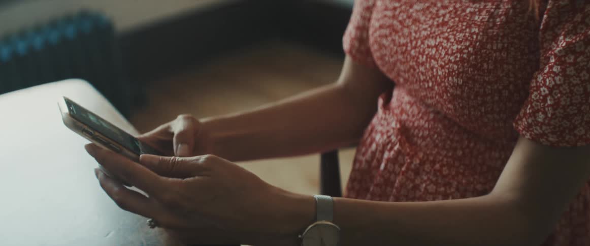 Woman sitting at the desk uses a smartphone