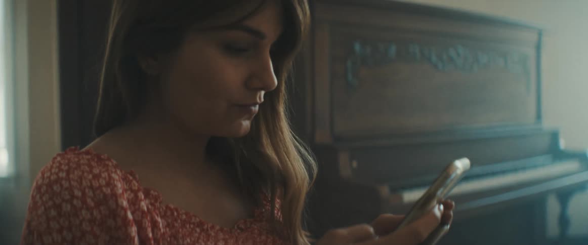 A woman scrolls through her cell phone in her home