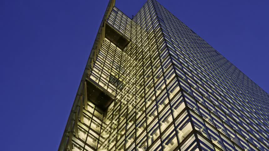 A bright blue sky above a building with glass window facade and jut outs