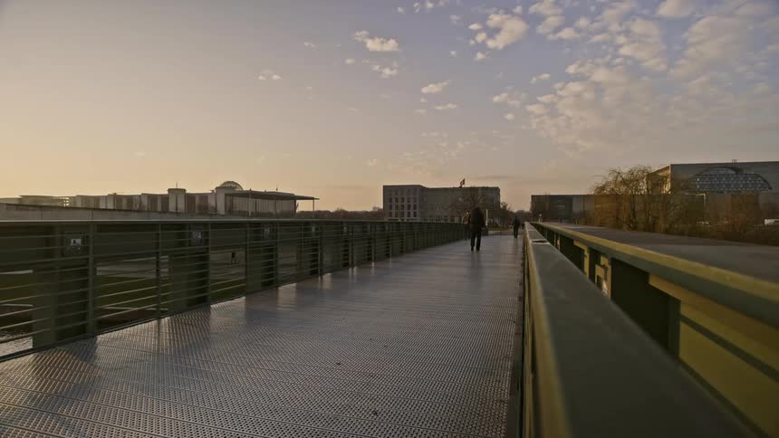 People walk and run on a boardwalk near buildings