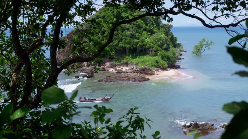 A boat floats by a beach in a tropical area