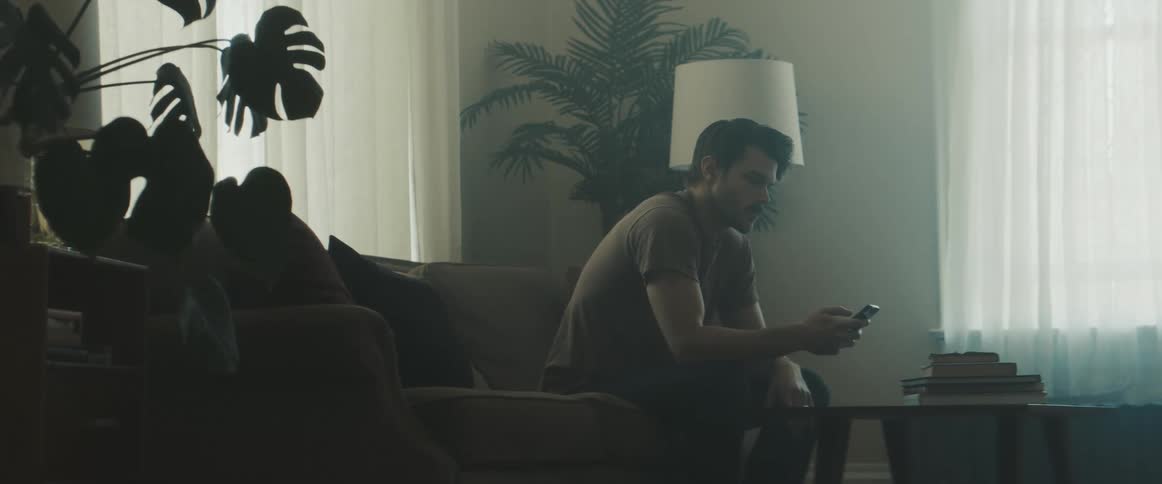 Man uses smart phone while sitting on the couch in the living room