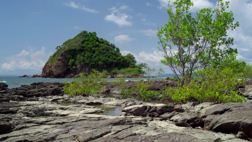 An islet sits off the coast of a rocky shoreline