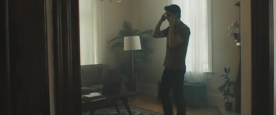 Man talks on smartphone on a dimly lit living room in a house