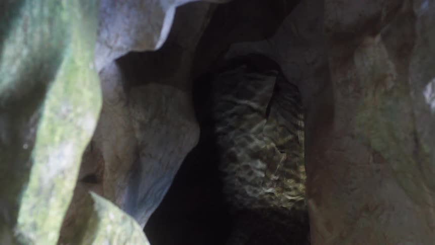 Water ripples in underground river at base of opening in rock