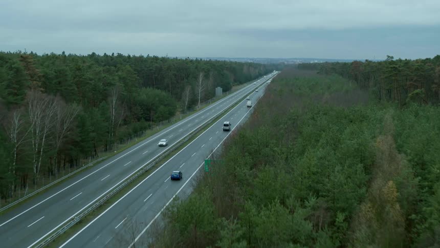 Traffic drives down a highway that runs through a forest