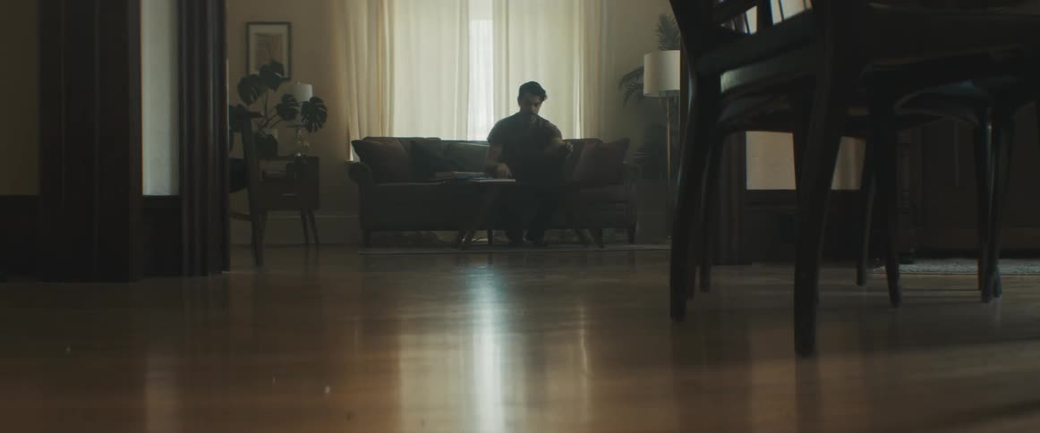 A man sits quietly in the couch inside his home looking bored and lonely
