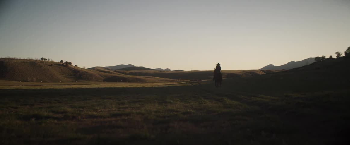 A person rides a horse across the land
