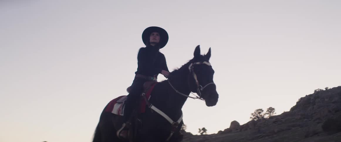 A woman is riding a horse in a rural area