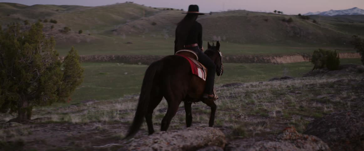 A woman rides her horse across the country side