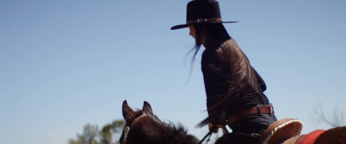 A woman gets on her horse to ride it