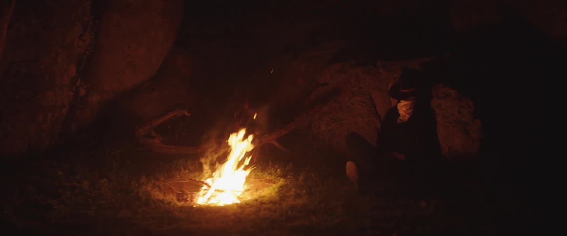 Woman sits by the campfire at night
