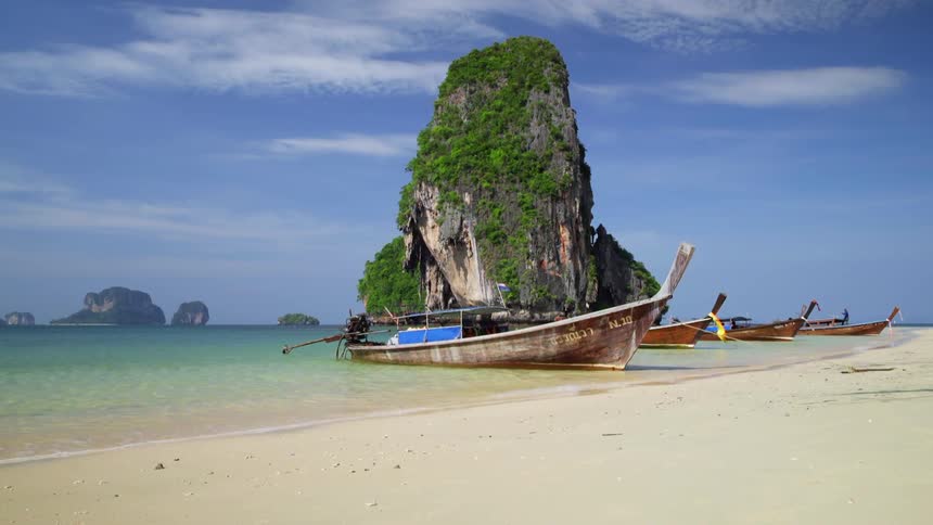 Small boats are moored near beach and vegetation covered islet