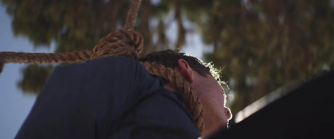 A man sits with a noose around his neck