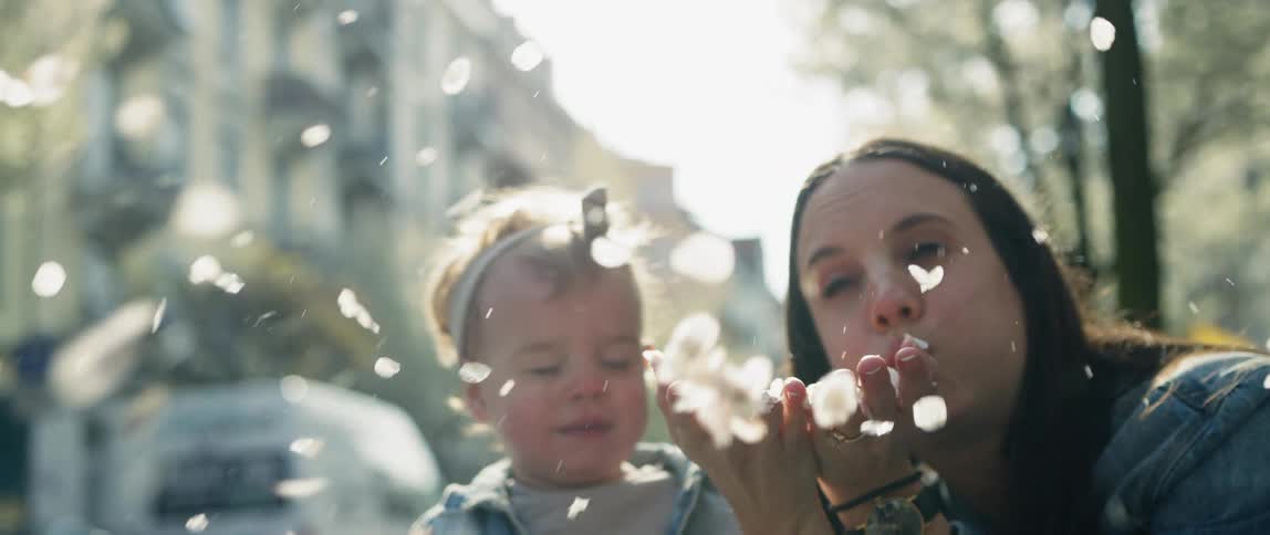A woman with her son and daughter blows a handful of petals in the air