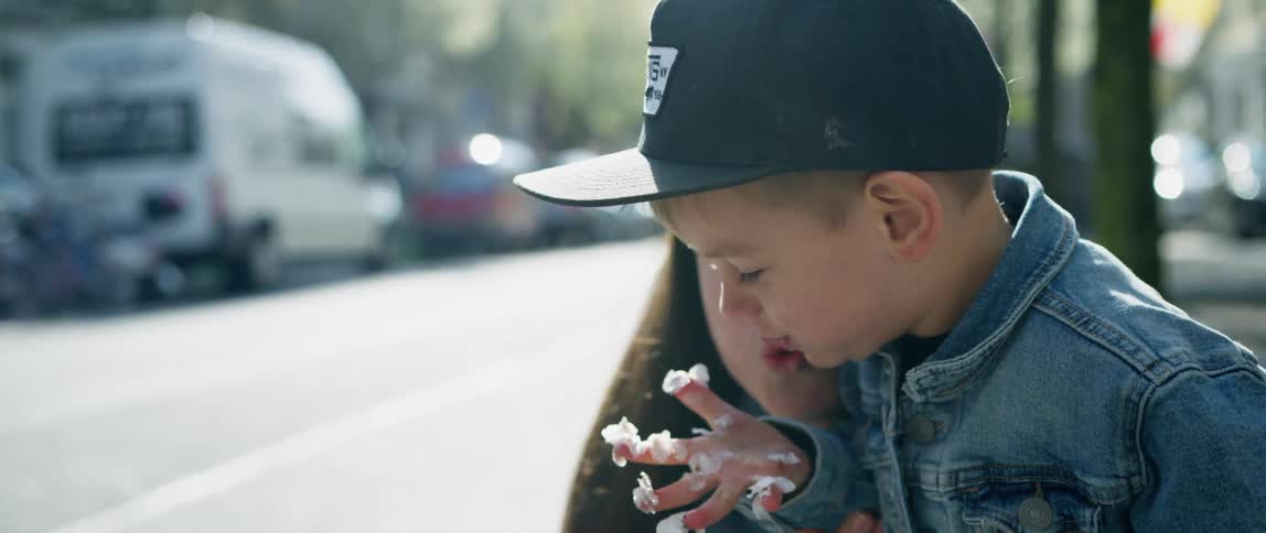 Mother and son play with white flower petals on the street of a city