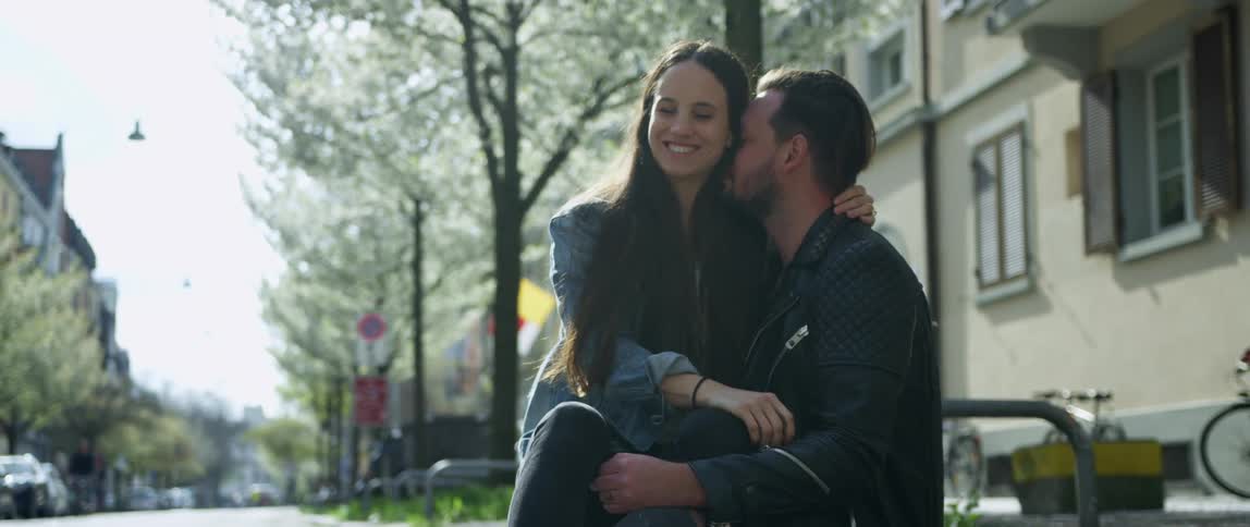 Woman sits her boyfriends lap in the street