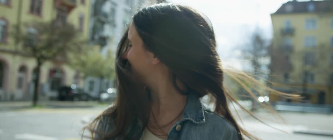 A white woman stands in a neighborhood of a city and shakes her head back and forth