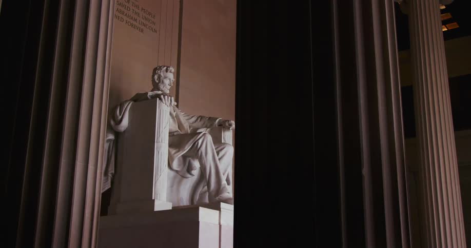 A pale stone statue sits inside a ornate building
