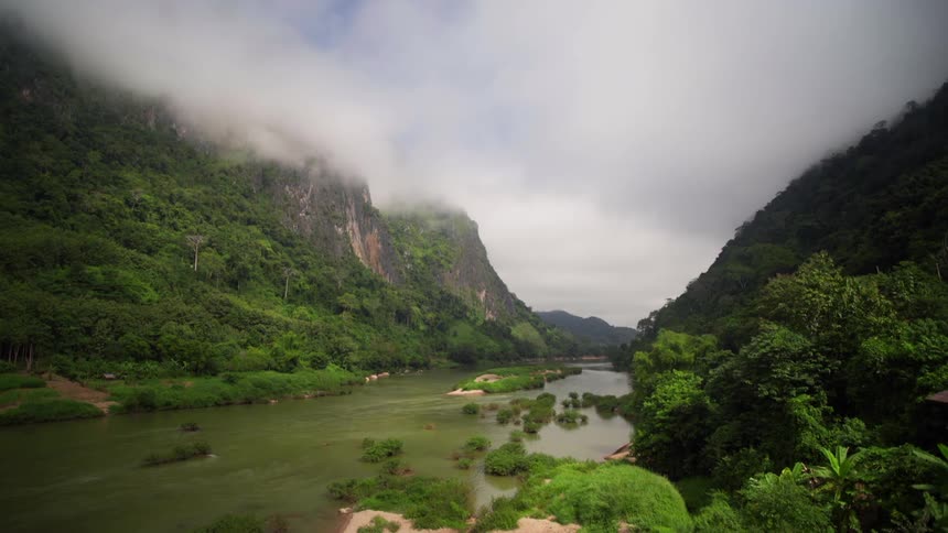 A river runs between two mountains covered in forests