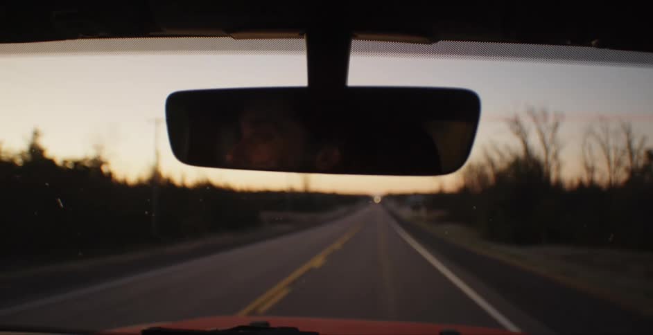 Man drives a car on a highway at dusk