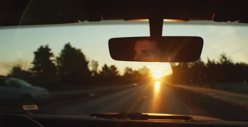 A man is driving a car at dusk