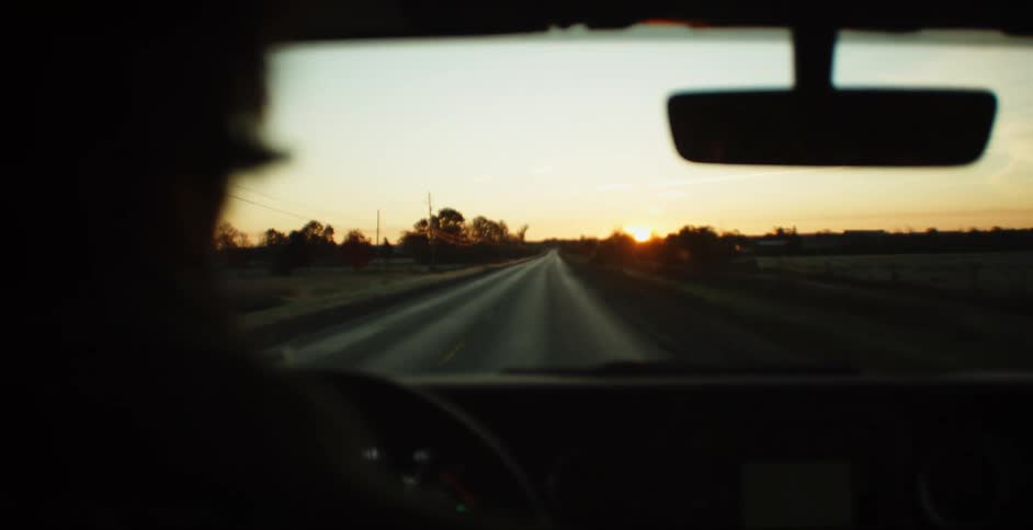Man drives his car on the highway at sunset