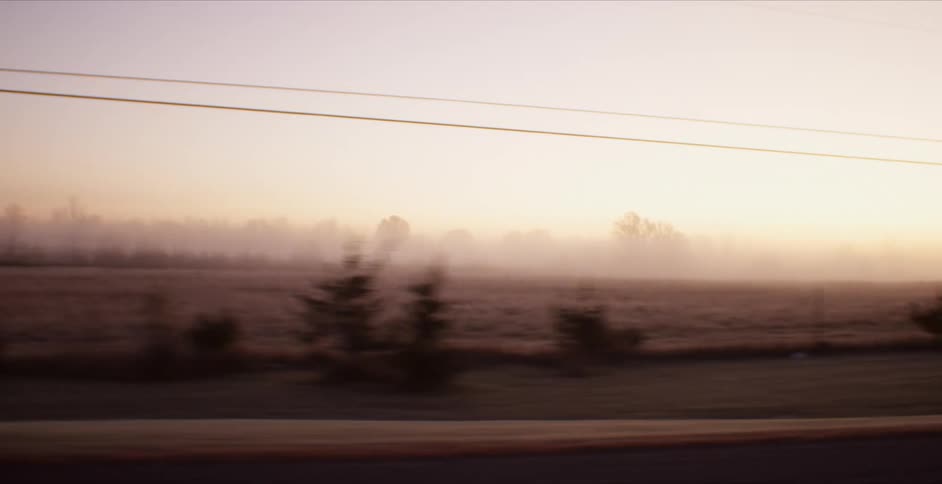 A car travels on a rural road at sunset