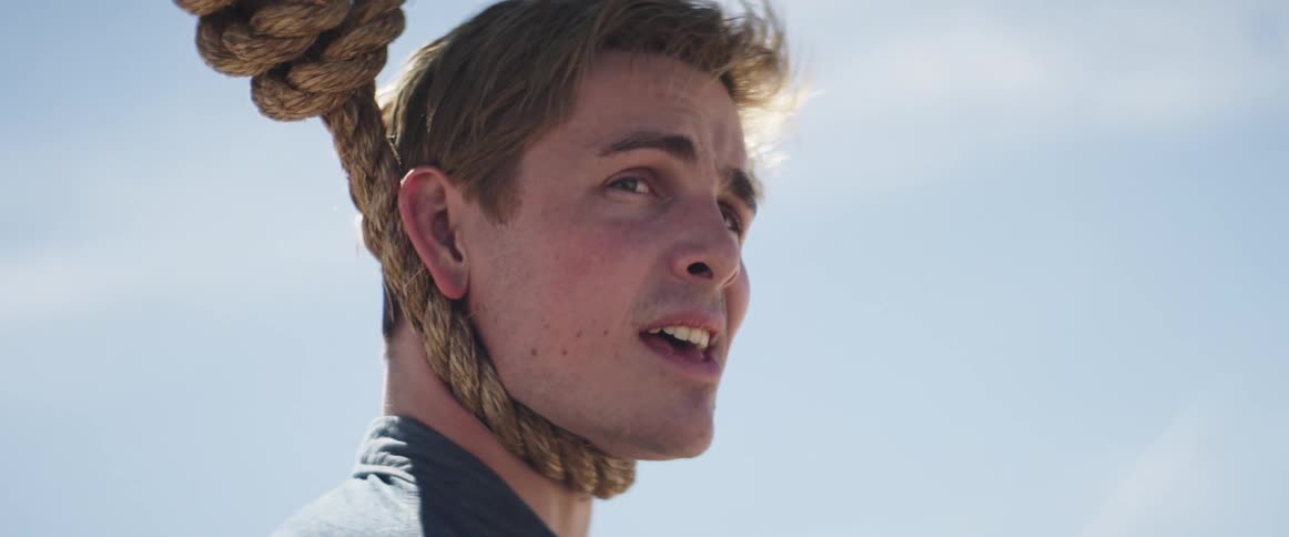 A white man looks around with a noose around his neck