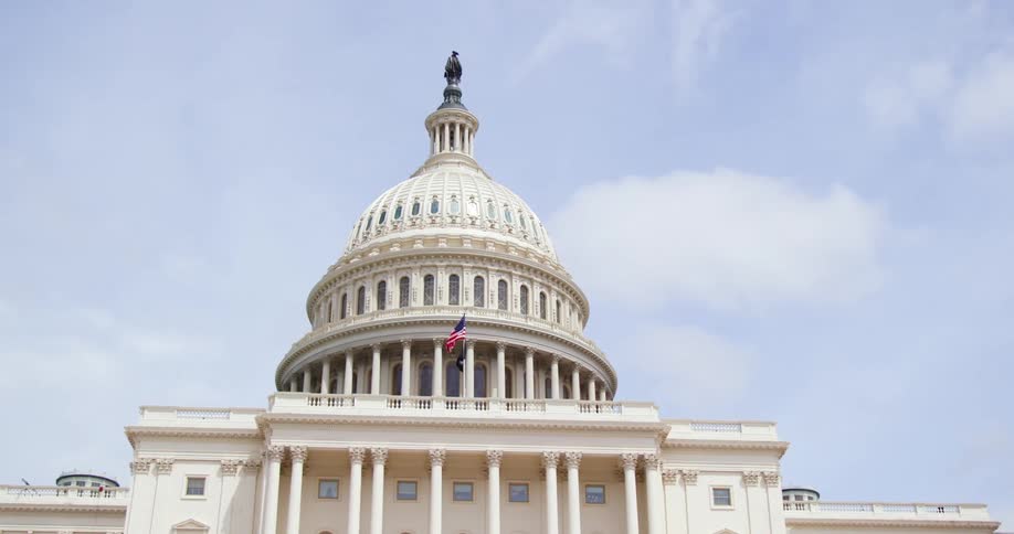 An american flag billows in the wind on top of a government building