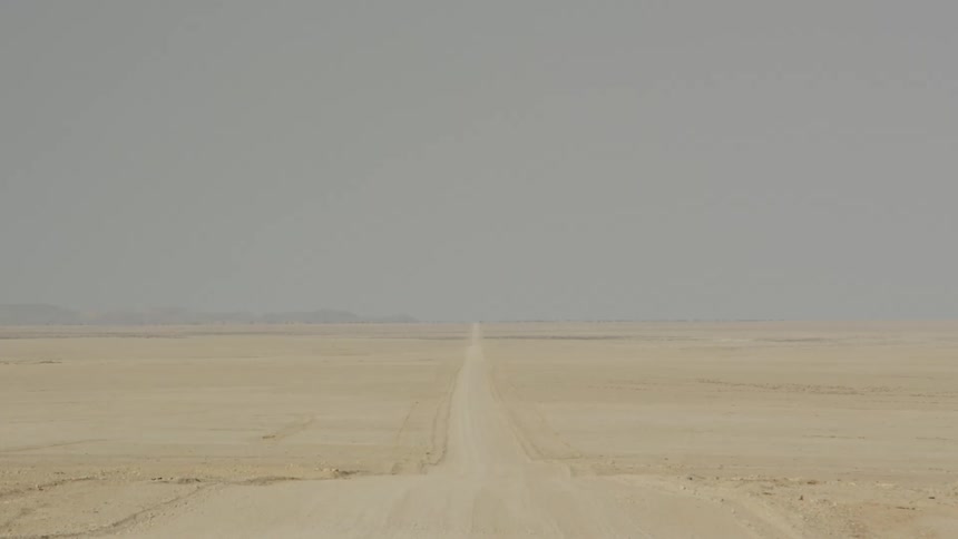 A long dusty road stretches through the desert