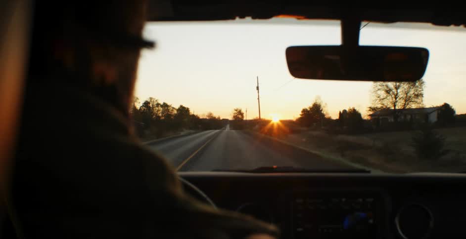 Man drives his car on a highway at sunset
