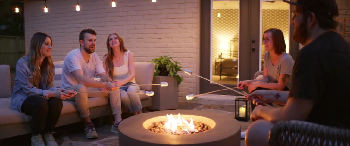 A group of friends roast marshmallows outside a house